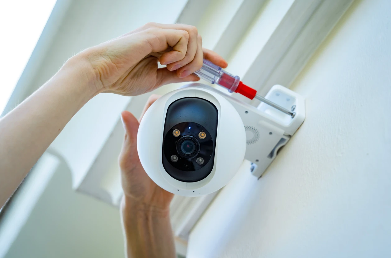 Scène extérieure résidentielle avec caméra de surveillance professionnelle au premier plan surveillant une propriété privée