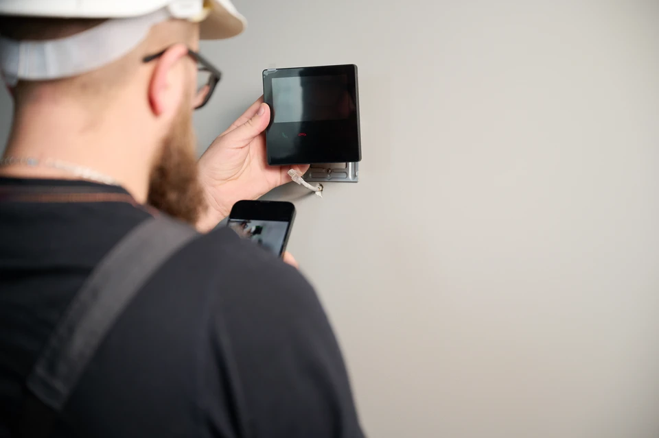 Main feminine tenant un smartphone blanc montrant une application de système de sécurité domestique avec flux vidéo de surveillance multi-caméras