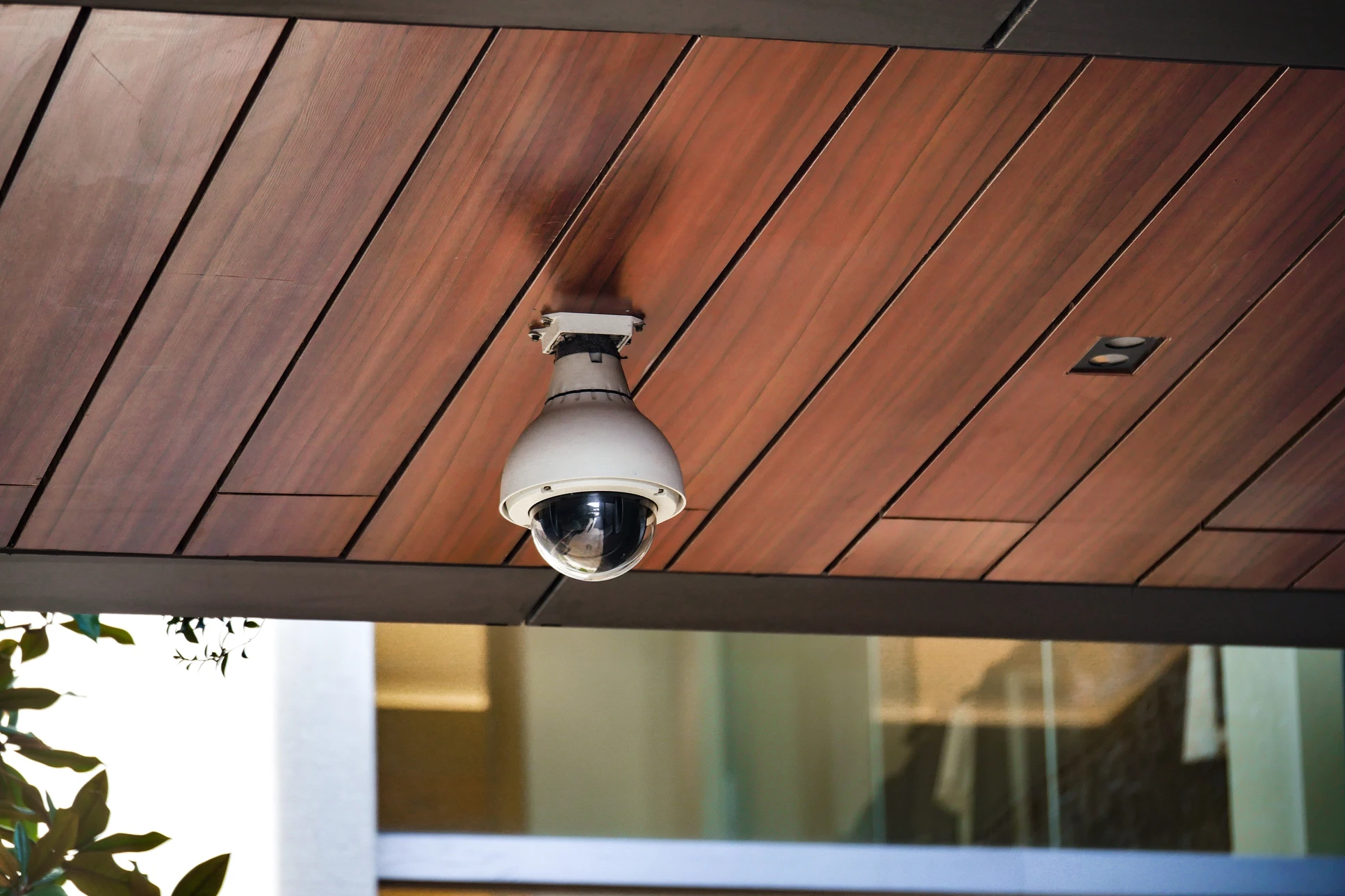 Scène extérieure résidentielle avec caméra de surveillance dôme PTZ au premier plan surveillant une maison moderne à deux étages