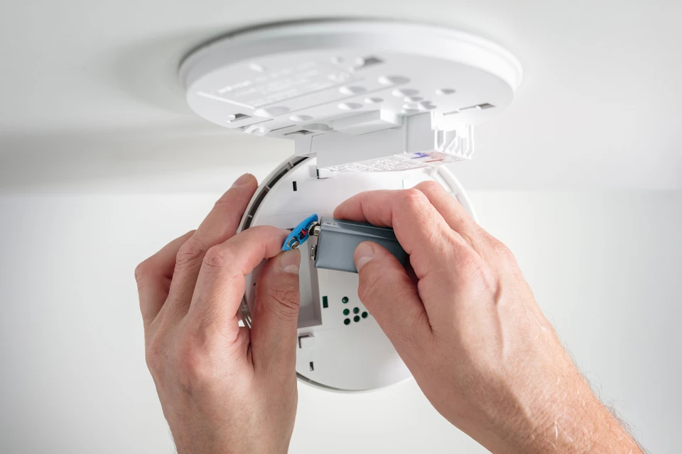 Technicien en casque de sécurité blanc effectuant la maintenance d'un système de sécurité incendie dans un local technique