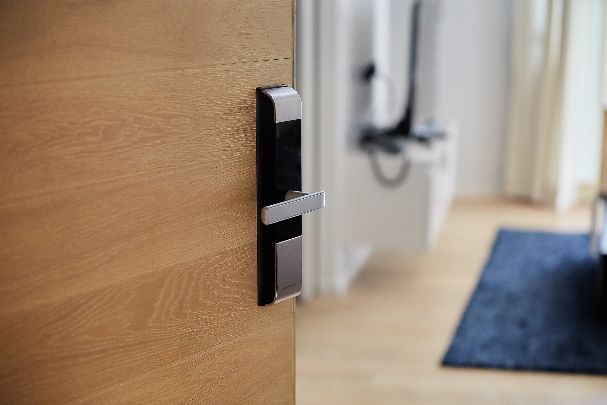 Technicien en uniforme bleu installant une serrure électronique sur porte intérieure d'appartement moderne