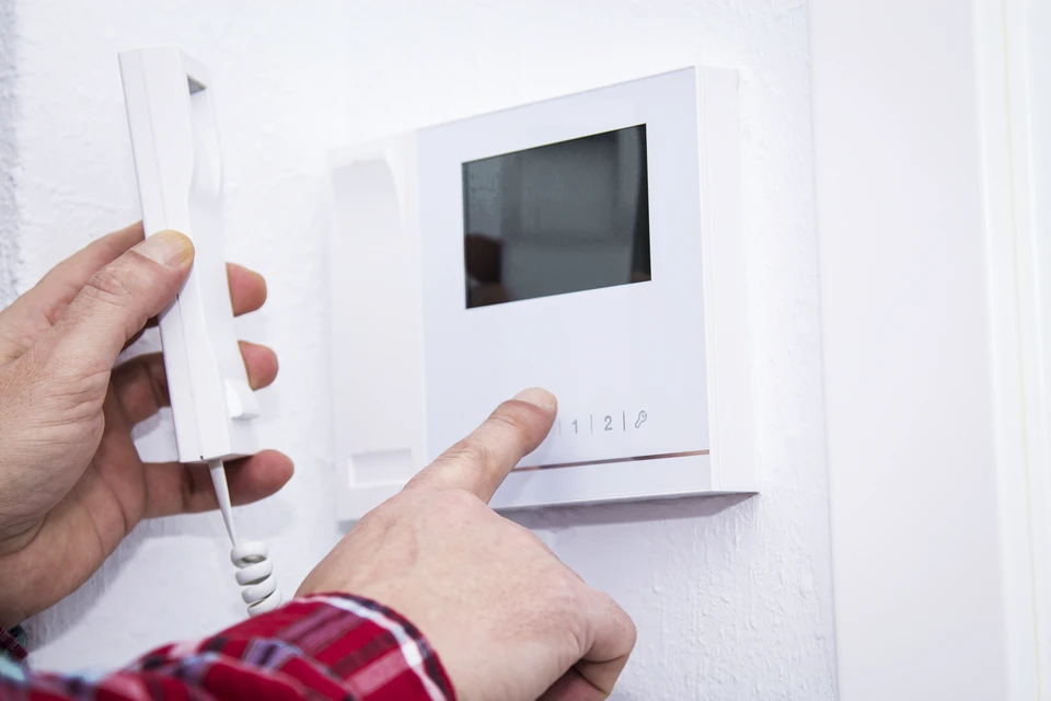 Photo réaliste d'une porte professionnelle de locaux d'entreprise équipée d'un dispositif de contrôle d'accès moderne (lecteur de badge RFID, clavier digicode ou reconnaissance biométrique) intégré au-dessus ou à côté de la poignée. Un professionnel ou un collaborateur peut être représenté en train de présenter un badge à proximité du lecteur. L'arrière-plan doit montrer un hall d'entrée professionnel, net et sécurisé, avec éclairage approprié mettant en évidence le système de contrôle d'accès.